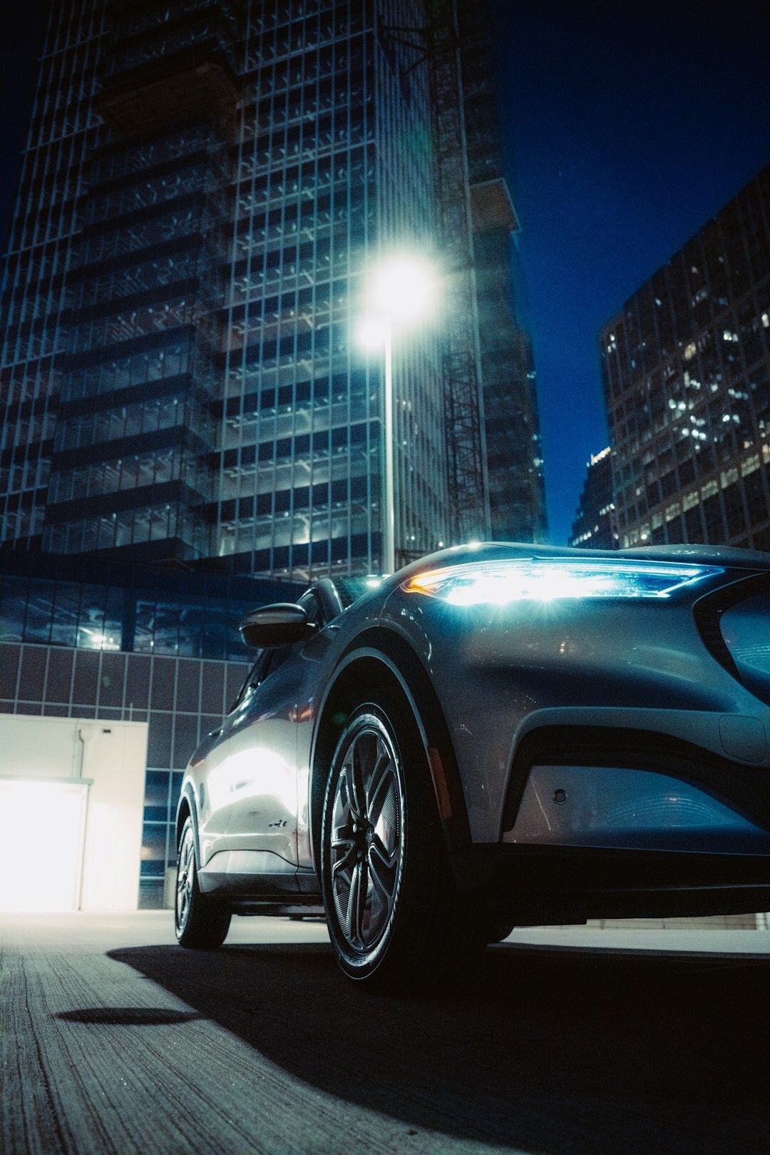 Electric blue supercar parked on a rooftop overlooking the city at night